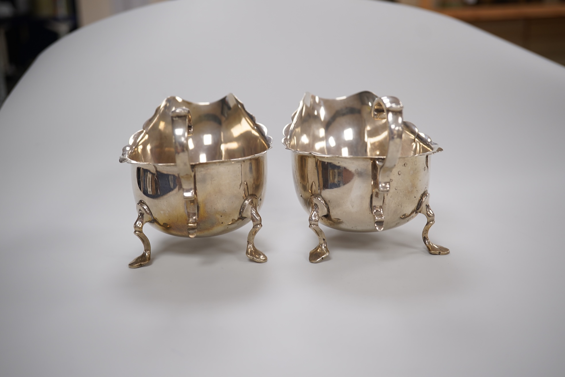 A pair of George V silver sauce boats, with flying scroll handles and pair of matching sauce ladles, Martin, Hall & Co, Sheffield, 1922/3, 10.1oz.